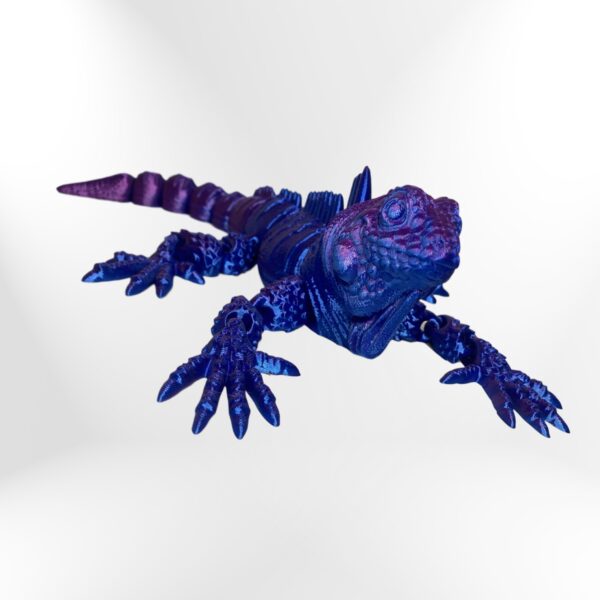 Blue iguana sculpture with intricate detailing on scales and limbs, artfully posed against a neutral background
