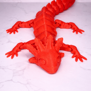 Red 3D printed Axolotl figurine with articulated joints, lying on a white marble surface