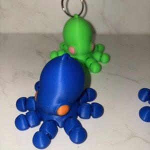 AUTO-DRAFT: 3D printed octopus figurines, blue and green, with articulated tentacles.