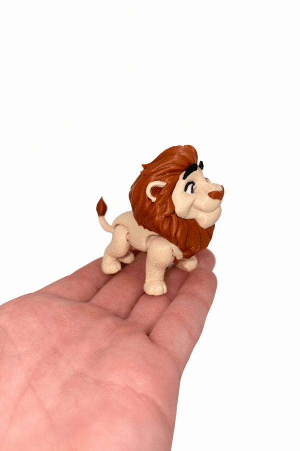 Lion toy figure with brown mane, standing on a hand.
