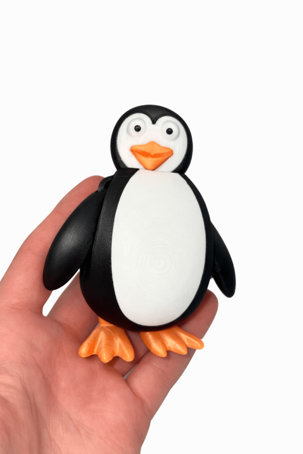 Penguin figure held in hand. 3D printed toy.