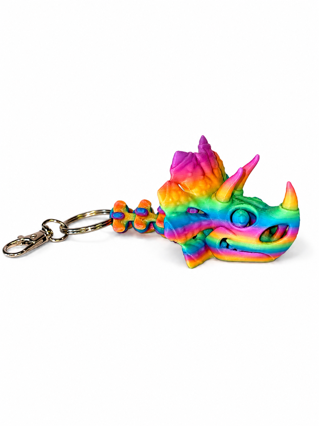 ChatGPT Image Jul 16 2026 11_17_00 AM Rainbow colored 3D printed triceratops skull keyring with articulated tail.