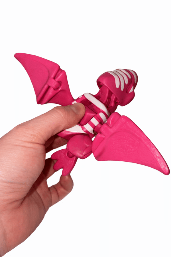 AUTO-DRAFT: Pink toy dinosaur skeleton with wings, held in hand.